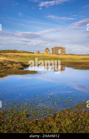 Die Ruinen der St. Dwynwen Kirche spiegeln sich im Wasser auf Llanddwyn Island, Isle of Anglesey, Nordwales Stockfoto
