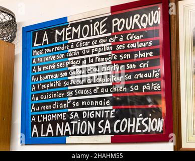 Ein handgemachtes Plakat in den Farben der französischen Flagge mit dem Titel "La Mémoire Pourquoi" (Erinnerung, warum) hängt an der Wand in der privaten Sammlung von Kader Zennaf in Saint-Chamond, Departement Loire, Frankreich. Der Text endet mit den Zeilen "A l'homme sa dignité, à la nation sa cohésion" (Dem Menschen seine Würde, der Nation ihren Zusammenhalt). Stockfoto