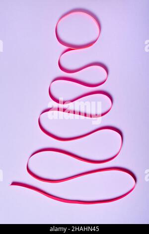 Weihnachtsbaum aus rosa Band auf lila Papier Hintergrund Stockfoto