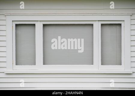 Typisches weißes Holzfenster an der Wetterbrettwand Stockfoto