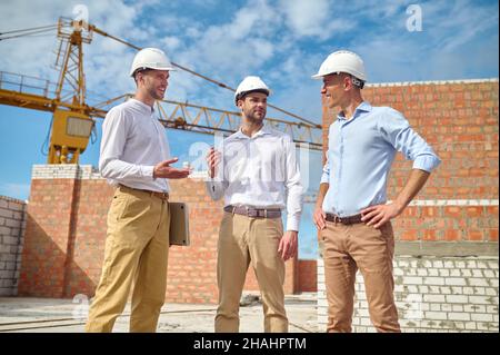 Drei Männer kommunizieren auf der Baustelle Stockfoto
