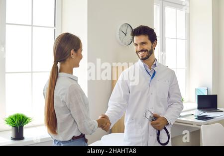 Der Arzt schüttelt die Hände, während seine Patientin sie in einer modernen medizinischen Klinik willkommen heißt. Stockfoto