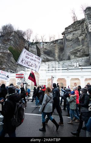 Salzburg, Österreich. 12th Dez 2021. Schild: „ Hände weg von unseren Kindern“. Aktivisten zünden ein Feuerwerk an. Am 12. Dezember 2021 nahmen etwa 4500 Personen an einer Demonstration gegen alle Covid-19-Maßnahmen wie Zwangsmasken oder die obligatorische Impfung in Salzburg Teil. Die Parteien MFG und FPOe organisierten den Protest. (Foto: Alexander Pohl/Sipa USA) Quelle: SIPA USA/Alamy Live News Stockfoto