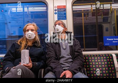 LONDON, GROSSBRITANNIEN. 13. Dezember 2021. Zwei Reisende in der Londoner U-Bahn tragen Schutzmasken, nachdem Premierminister Boris Johnson am Sonntagabend in einer Fernsehansprache in der Downing Street einen omicron-Notfall angekündigt hatte und ab dieser Woche ein Auffrischungsprogramm mit covid jabs für alle über 18 in England angeboten wird, um die zu bekämpfen Schnelle Ausbreitung der omicron-Variantenstamm. Kredit: amer ghazzal/Alamy Live Nachrichten Stockfoto