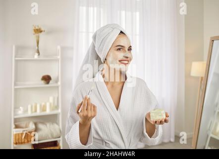 Schöne Frau am Morgen trägt feuchtigkeitsspendende Maske oder Creme auf das Gesicht mit Pinsel. Stockfoto