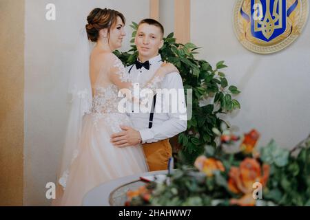 Hochzeit: Junges Paar in Liebe Braut und Bräutigam umarmen einander mit einem Blumenstrauß. Zwei Liebeherzen auf der Hochzeitszeremonie. Stylisch Stockfoto