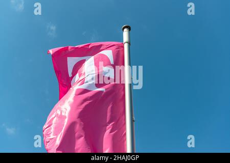 Fahne der Telekom in Magenta vor blauem Himmel Stockfoto