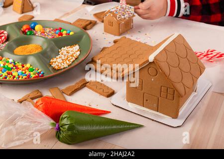 Kinder bauen und dekorieren ein Lebkuchenhaus zur Weihnachtszeit. Weihnachten Familientradition, Weihnachtshandwerk. Stockfoto