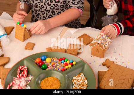 Kinder bauen und dekorieren ein Lebkuchenhaus zur Weihnachtszeit. Weihnachten Familientradition, Weihnachtshandwerk. Stockfoto