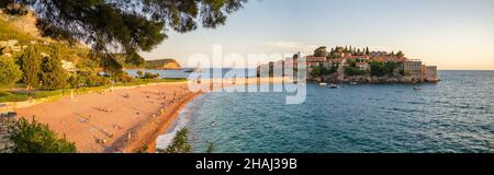 Panorama eines Strandes und der Insel Sveti Stefan bei Sonnenuntergang in Montenegro Stockfoto