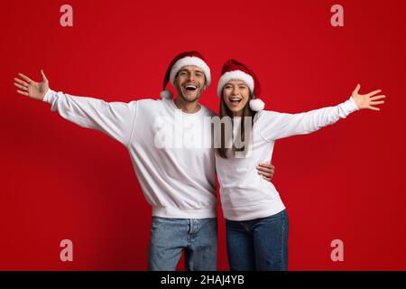 Frohe Weihnachten. Paar In Santa Hats, Die Hände Streuen Und Die Kamera Lächeln Stockfoto