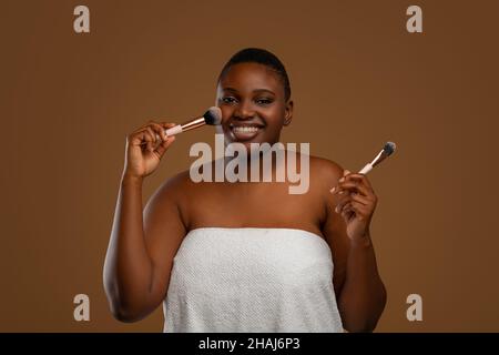 Porträt von schönen schwarzen molligen Frau mit Make-up-Pinsel Stockfoto