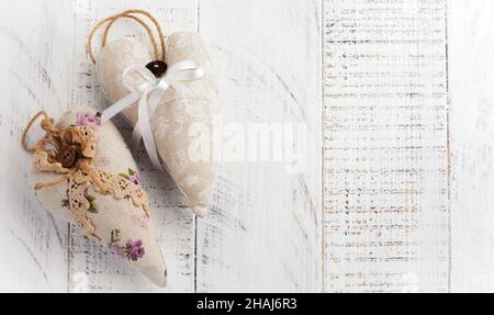 Gruppe festlicher Herzen aus verschiedenen Materialien, Stoff, Wolle, Holz, auf weißem Holzhintergrund. Selektiver Fokus. Vintage Valentinskarte. Draufsicht. Pl Stockfoto