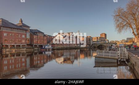 Riverside-Szene im King’s Staith in York. Wohnungen und Lagerhäuser spiegeln sich im Wasser und eine Brücke befindet sich in der Ferne. Stockfoto