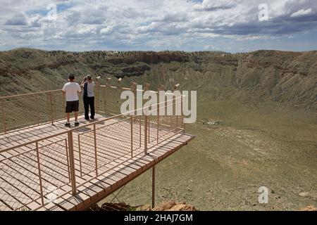 Zwei Menschen stehen an den Teleskopen auf dem Aussichtsterrasse am Meteor-Krater in der Nähe von Winslow im Norden von Arizona, USA. Der Krater-Rand zeigt umgestrichelte, lag Stockfoto