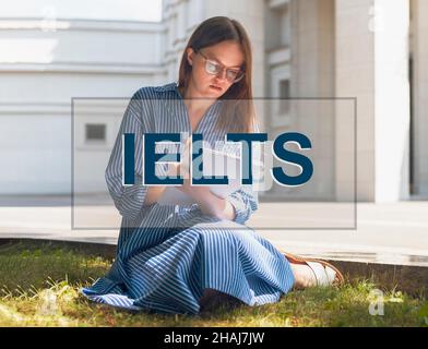 IELTS-Wort. Frau lernt, studiert und bereitet sich auf die englische Sprachprüfung vor. Stockfoto