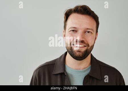 Porträt eines reifen bärtigen Mannes in legerer Kleidung, der vor dem weißen Hintergrund vor der Kamera lächelt Stockfoto