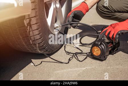 Reifenpumpe, die das Autorad aufpumpt. Reifenaufblasvorrichtung in männlichen Händen, Druck mit Manometer prüfen. Stockfoto