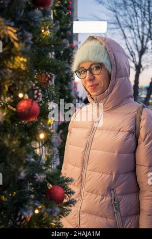 Hübsche Frau in der Nähe beleuchteten Neujahr dekoriert Fenster. Weihnachtsferien oder Shopping auf Neujahr oder Weihnachten Konzept Stockfoto