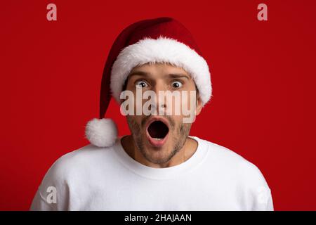 Schockierendes Angebot. Stauned Man In Santa Hat Mit Spannung Die Kamera Angeschaut Stockfoto