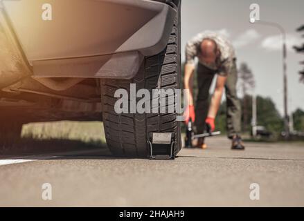 Mann in der Nähe von Autoreifen mit Auto-Jack-Werkzeug, Low-Angle-Ansicht. Stockfoto