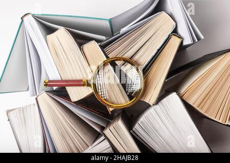 Lupe über verschiedenen Büchern. Konzept von Wissen, Forschung und Studium. Stockfoto