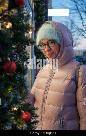 Hübsche Frau in der Nähe beleuchteten Neujahr dekoriert Fenster. Weihnachtsferien oder Shopping auf Neujahr oder Weihnachten Konzept Stockfoto