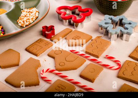 Lebkuchenhauskekse, die bereit sind, mit farbiger königlicher Glasur dekoriert zu werden. Traditionelles weihnachtshandwerk für die Familie. Stockfoto