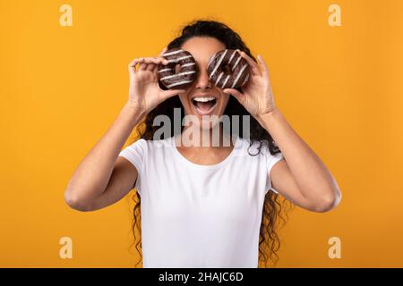 Happy Latin Lady Bedeckt Die Augen Mit Donuts Im Studio Stockfoto