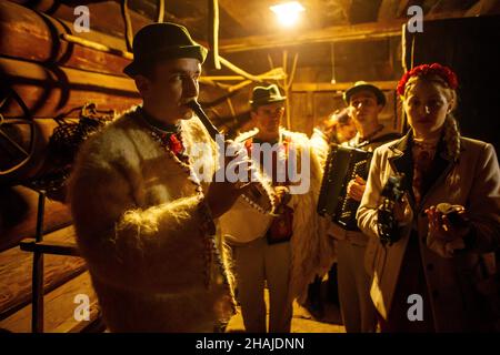 USCHHOROD, UKRAINE - 10. DEZEMBER 2021 - Menschen in traditionellen ukrainischen Kostümen spielen Musikinstrumente während der Andriivski Vechornytsi-Feier Stockfoto