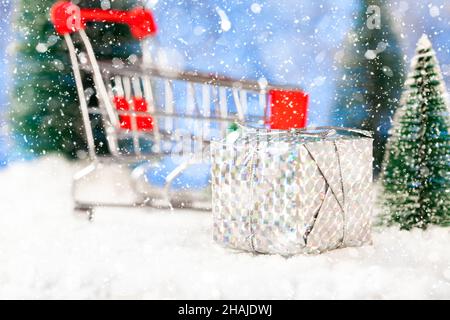 Neujahr und weihnachtseinkäufe für Geschenke, Supermarkt-Korb mit Geschenkbox auf Schnee, Konzept Stockfoto