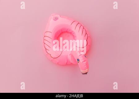 Strandzusammensetzung im Sommer. Einfach minimales Design mit aufblasbarem Flamingo, isoliert auf pastellrosa Hintergrund. Pool Float Party, modisches Promi-Modekonzept. Platz für Kopien in flacher Lage in der Draufsicht Stockfoto