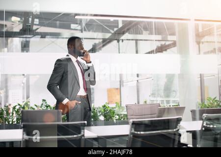 Fröhlicher, gutaussehender afroamerikanischer Geschäftsmann, der am Telefon spricht Stockfoto