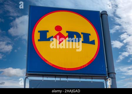 Fossano, Italien - 24. November 2021: Schild mit Lidl-Logo am blauen Himmel mit Wolken, Lidl Stiftung e Co. Kg ist eine europäische Supermarktkette aus Deutschland orig Stockfoto