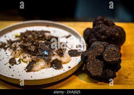 Frische Jakobsmuscheln mit Meersalz, schwarzem Pfeffer und Olivenöl und frisch rasierten schwarzen Trüffeln. Reduziert auf diese wenigen Zutaten, kommt der Geschmack des schwarzen Trüffels sehr gut zum Vorliegen. Aups, Frankreich Stockfoto