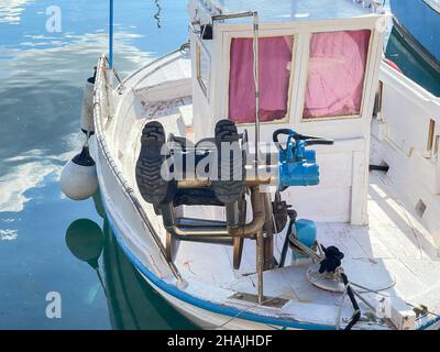 Gummistiefel trocknen auf Bow Winch in einem kleinen Holzboot, das in Ermoupolis, Syros Island, Griechenland, festgemacht ist Stockfoto