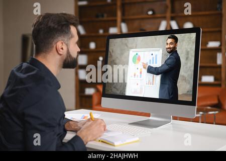 Virtuelle Konferenz. Junger Mann, der ein Headset trägt und einen pc für Videoanruf verwendet, hat Videobesprechung mit mehreren Personen zusammen. Remote-Work-Konzept Stockfoto