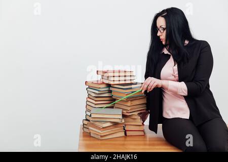 Weibliche Lehrerin im College-Tisch mit Büchern zum Lernen Stockfoto