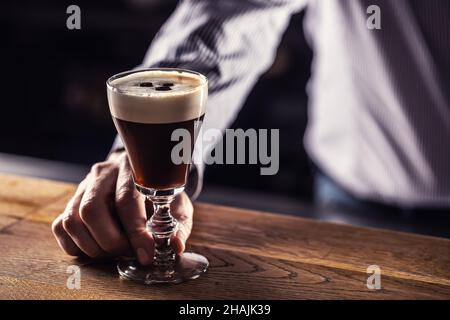 Der Barkeeper serviert Gästen im Café zubereiteten irischen Kaffee. Stockfoto