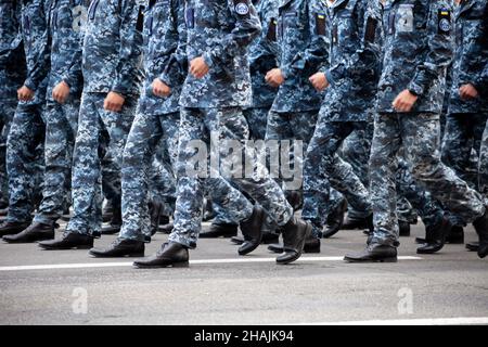 Selektiver Fokus. Bewegungsunschärfe. Moderne militärische Schuhe auf Soldaten. Ein Soldat in Uniform marschiert in der Parade ein. Menschen in der Menge. Stiefel am Fuß. Stockfoto