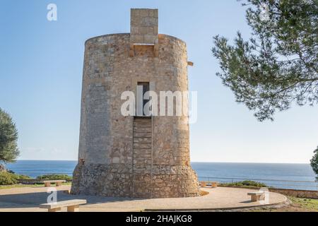 Gesamtansicht des mittelalterlichen Turms Torre Nova im mallorquinischen Ferienort Cala Santanyi, an einem sonnigen Tag mit dem Mittelmeer im Hintergrund Stockfoto