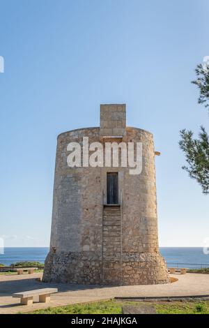 Gesamtansicht des mittelalterlichen Turms Torre Nova im mallorquinischen Ferienort Cala Santanyi, an einem sonnigen Tag mit dem Mittelmeer im Hintergrund Stockfoto