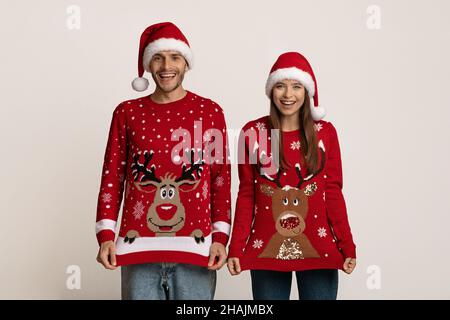 Porträt Von Lustigen Paar Trägt Rentier Hässliche Weihnachts Pullover Und Santa Hüte Stockfoto