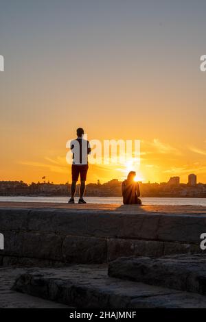 Wunderschöner Sonnenuntergang am Pier von Tamariz Beach, in Estoril, Portugal, und zwei Leute, die nachdenklich sind Stockfoto