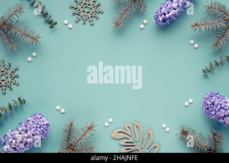 Grüner Minzpapier-Hintergrund mit Eukalyptus, Tannenzweigen und blauen Hyazinthen-Blüten. Zucker Schneeflocken und Holz exotische Blätter. Winterliche Dekoration Stockfoto