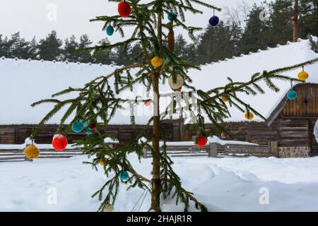 Сhristmas Baum mit bunten handgefertigten Kugeln aus Garn verziert. Helles Garn an einem Tannenbaum hängen clews verschiedener Farben Stockfoto