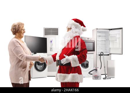 Ganzkörperaufnahme des weihnachtsmannes, der mit einer älteren Frau die Hände schüttelt, vor elektrischen Haushaltsgeräten, isoliert auf weißem Hintergrund Stockfoto