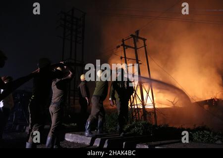 Kalkutta, West Bangal, Indien. 13th Dez 2021. Feuerwehrleute halten einen Schlauch, um Flammen zu entfachen, als im Power House und in der Nähe einer Wachsfabrik in Howrah, Westbengalen, ein massives Feuer ausbrach. (Bild: © Dipa Chakraborty/Pacific Press via ZUMA Press Wire) Bild: ZUMA Press, Inc./Alamy Live News Stockfoto