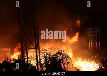 Kalkutta, West Bangal, Indien. 13th Dez 2021. Feuerwehrleute halten einen Schlauch, um Flammen zu entfachen, als im Power House und in der Nähe einer Wachsfabrik in Howrah, Westbengalen, ein massives Feuer ausbrach. (Bild: © Dipa Chakraborty/Pacific Press via ZUMA Press Wire) Bild: ZUMA Press, Inc./Alamy Live News Stockfoto