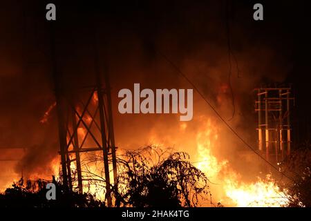 Kalkutta, West Bangal, Indien. 13th Dez 2021. Feuerwehrleute halten einen Schlauch, um Flammen zu entfachen, als im Power House und in der Nähe einer Wachsfabrik in Howrah, Westbengalen, ein massives Feuer ausbrach. (Bild: © Dipa Chakraborty/Pacific Press via ZUMA Press Wire) Bild: ZUMA Press, Inc./Alamy Live News Stockfoto